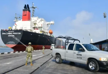 Buque en puerto con vigilancia militar.